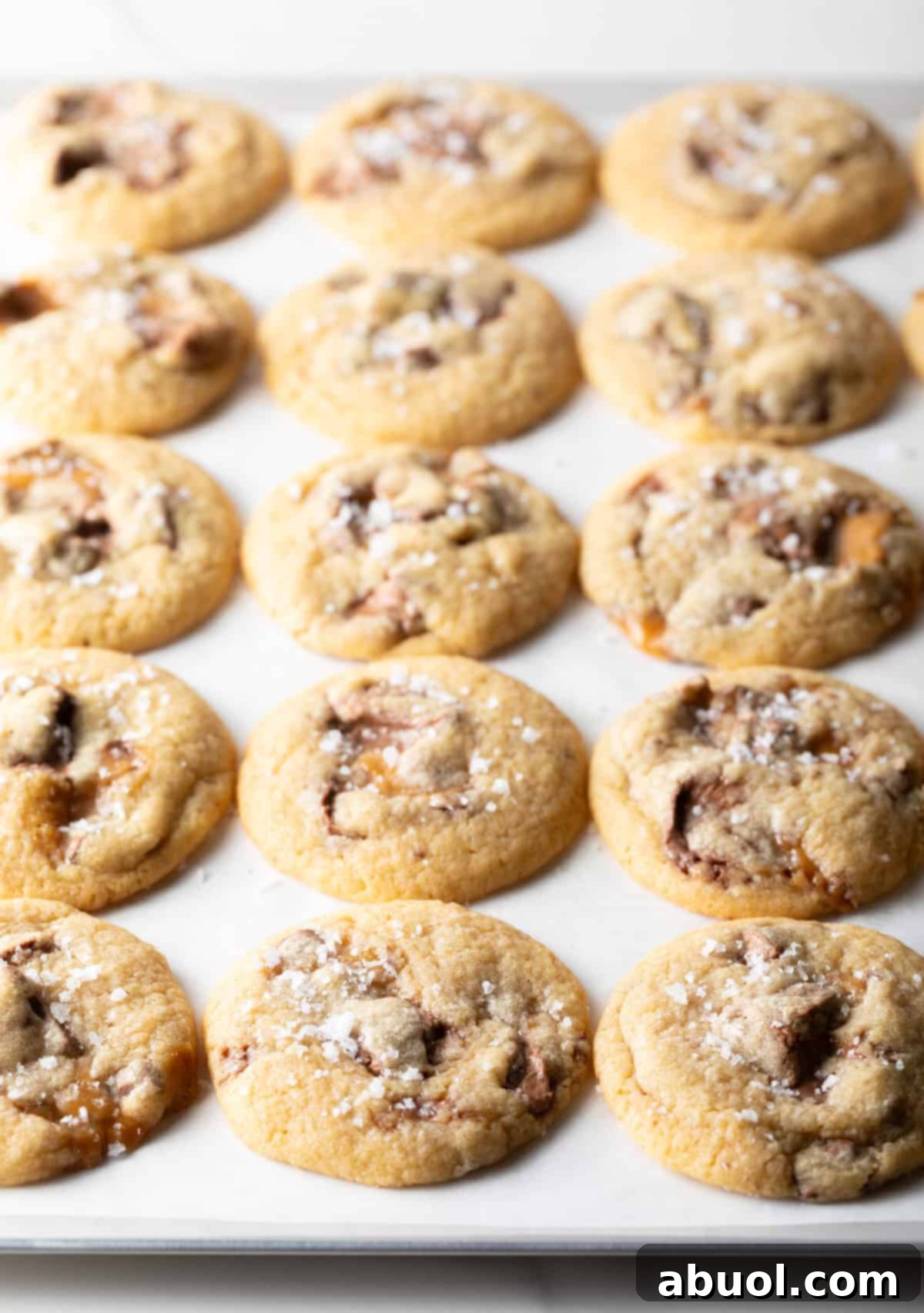 Freshly baked Milky Way cookies on a parchment-lined cookie sheet.