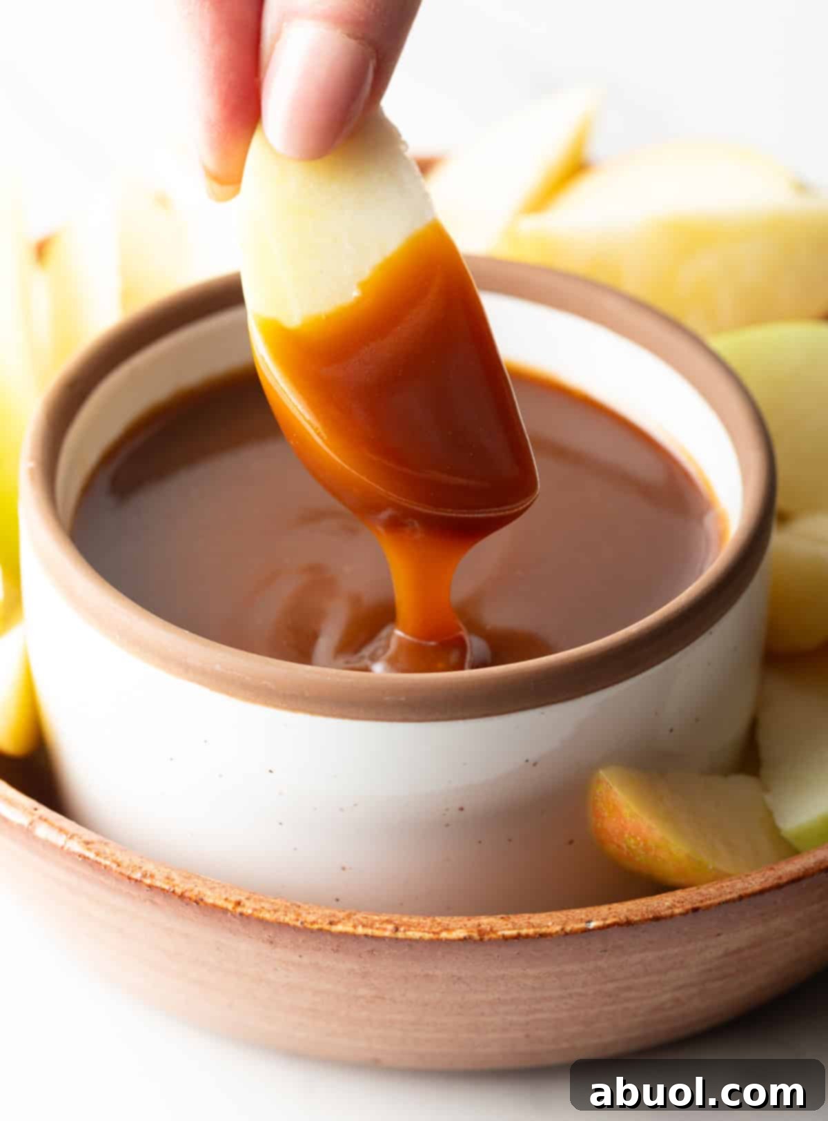 An apple slice dipped into salted caramel sauce