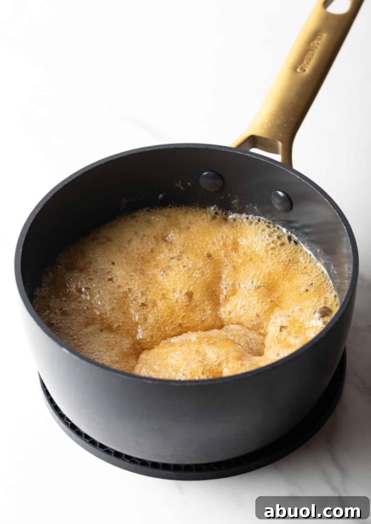 A mixture of sugar and water bubbling in a black pan