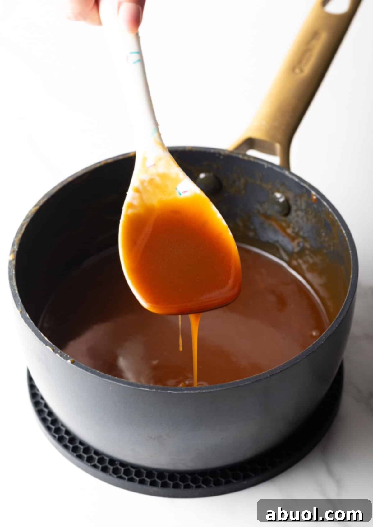 A white spatula holding salted caramel sauce