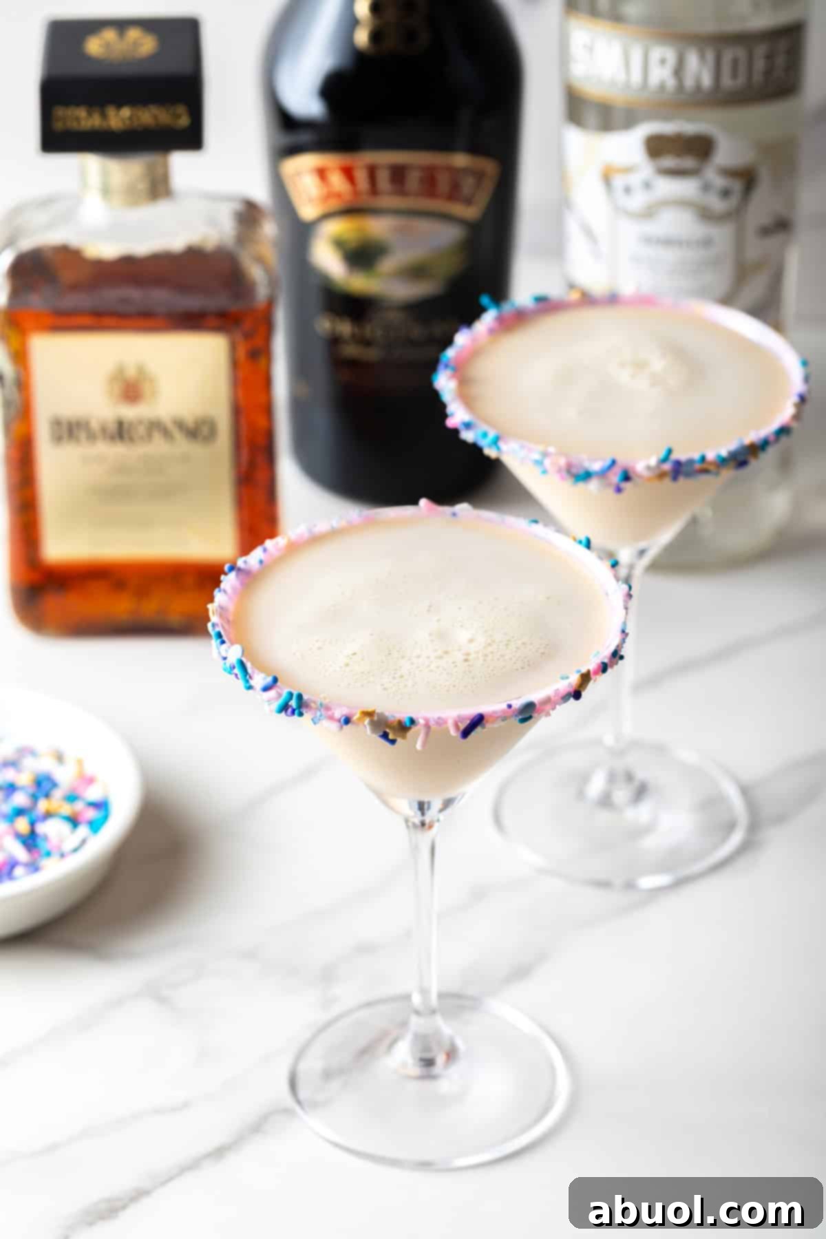 Two sugar cookie martinis lined with festive sprinkles, showcasing the colorful and appealing presentation of the finished cocktail.