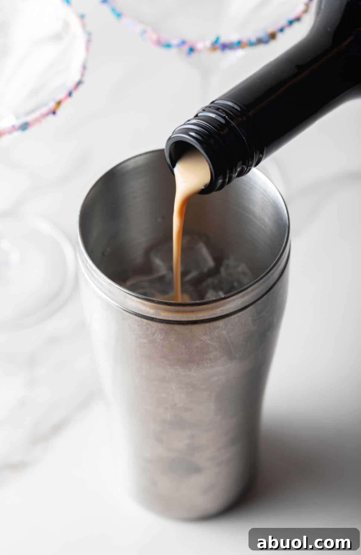 Bailey's Irish Cream being poured into a cocktail shaker, showcasing the first step in creating the Sugar Cookie Martini.