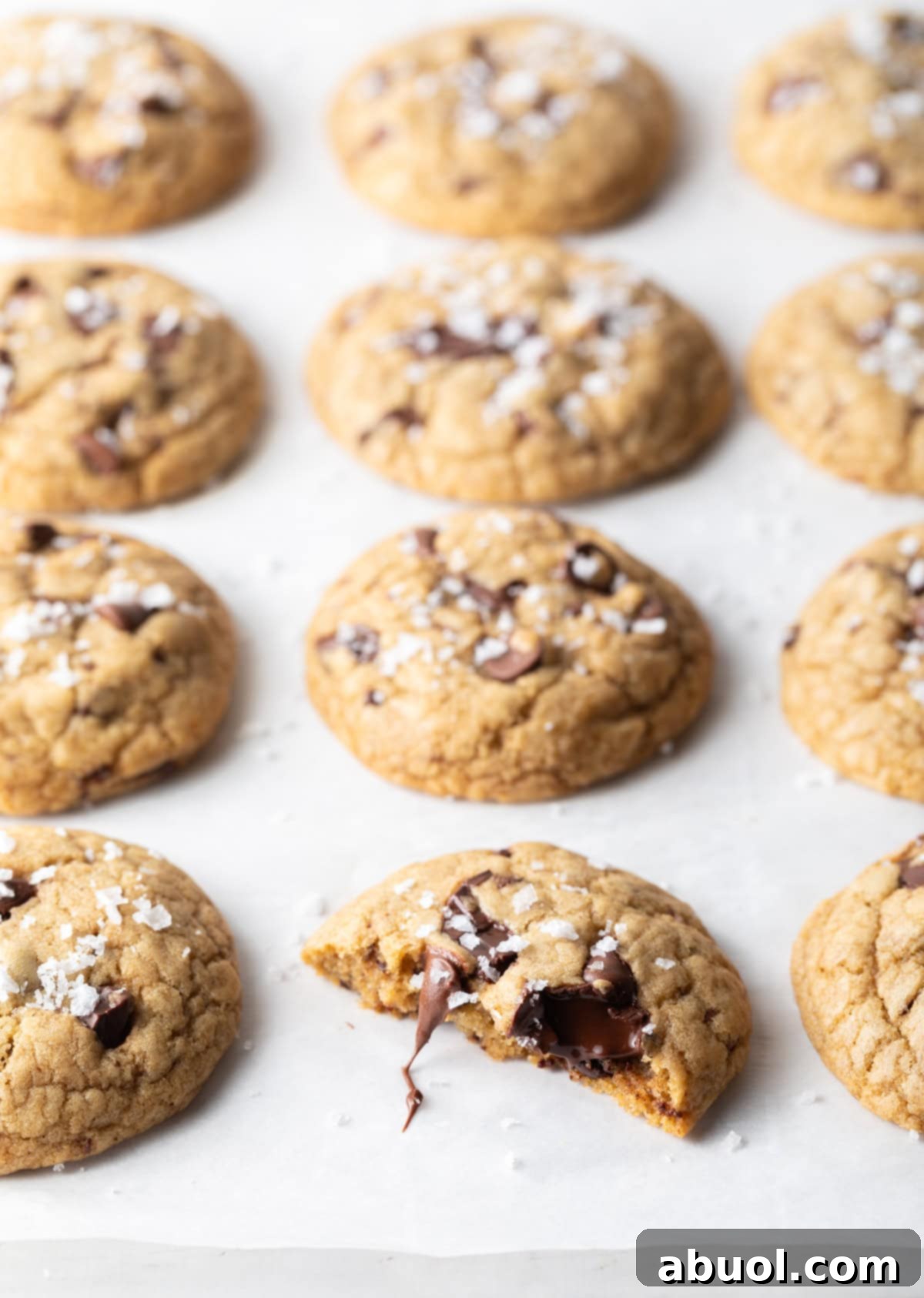 Top-down view of brown sugar chocolate chip cookies on a baking sheet, with one cookie broken in half.