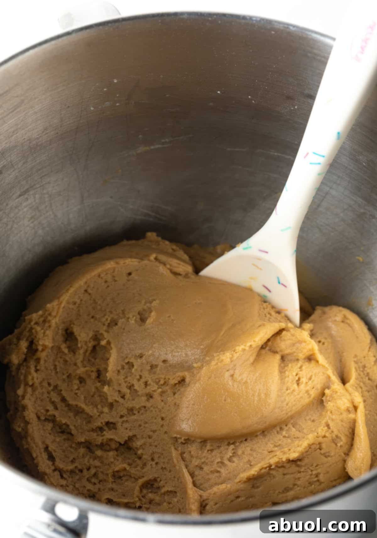 Brown sugar cookie dough in a metal mixing bowl with a spatula.