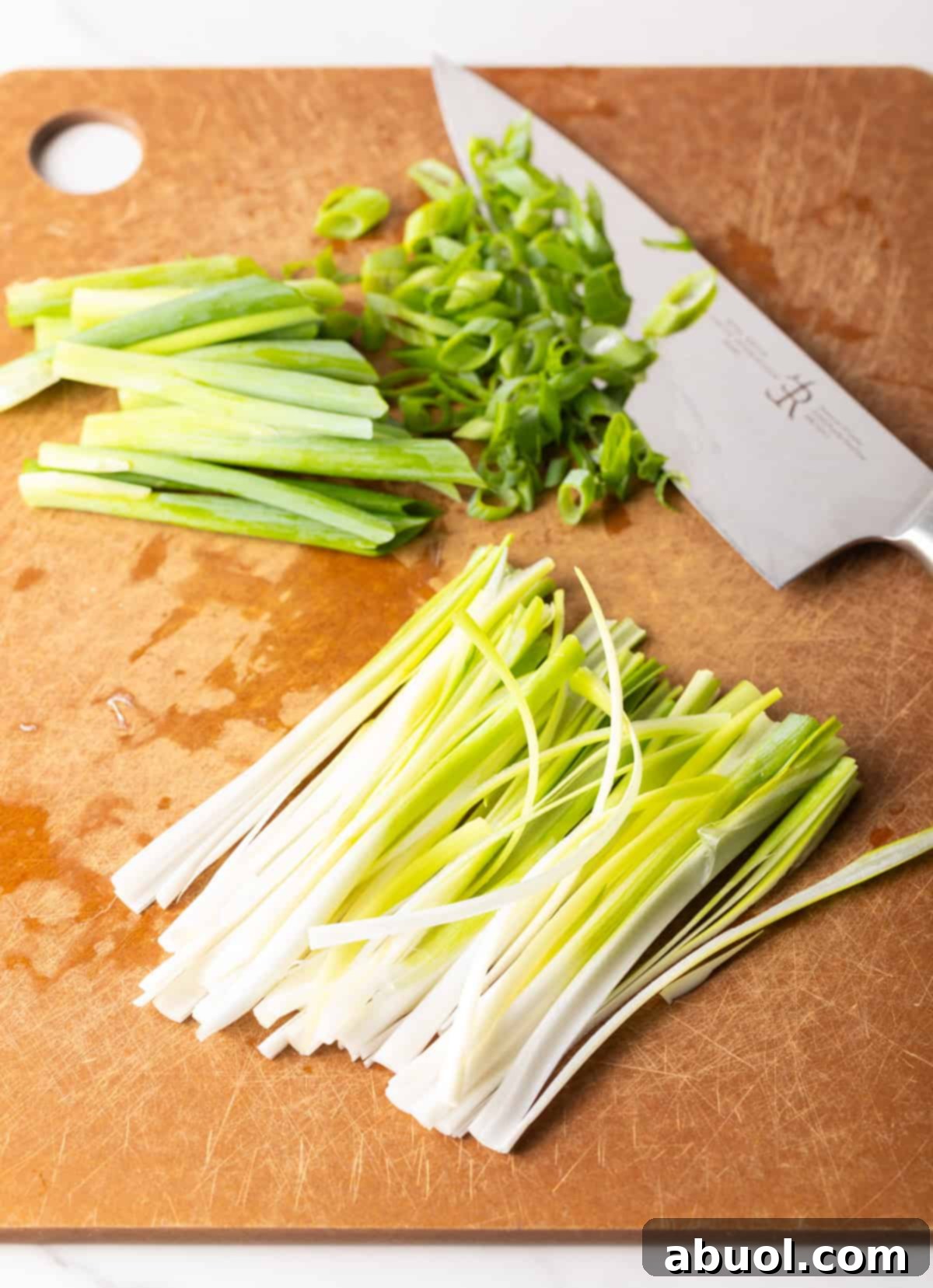 Chopped green onions on a cutting board next to a knife.