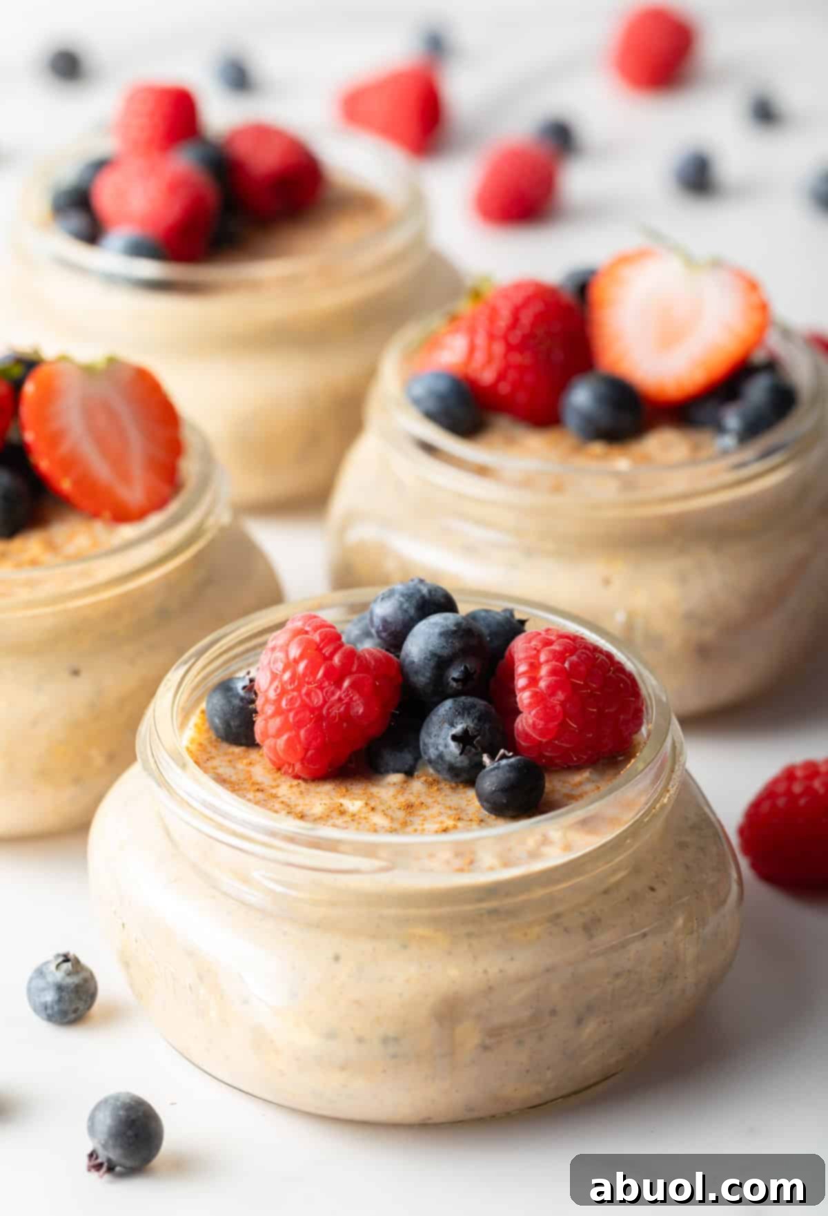 Small jars of high-protein overnight oats topped with raspberries and blueberries