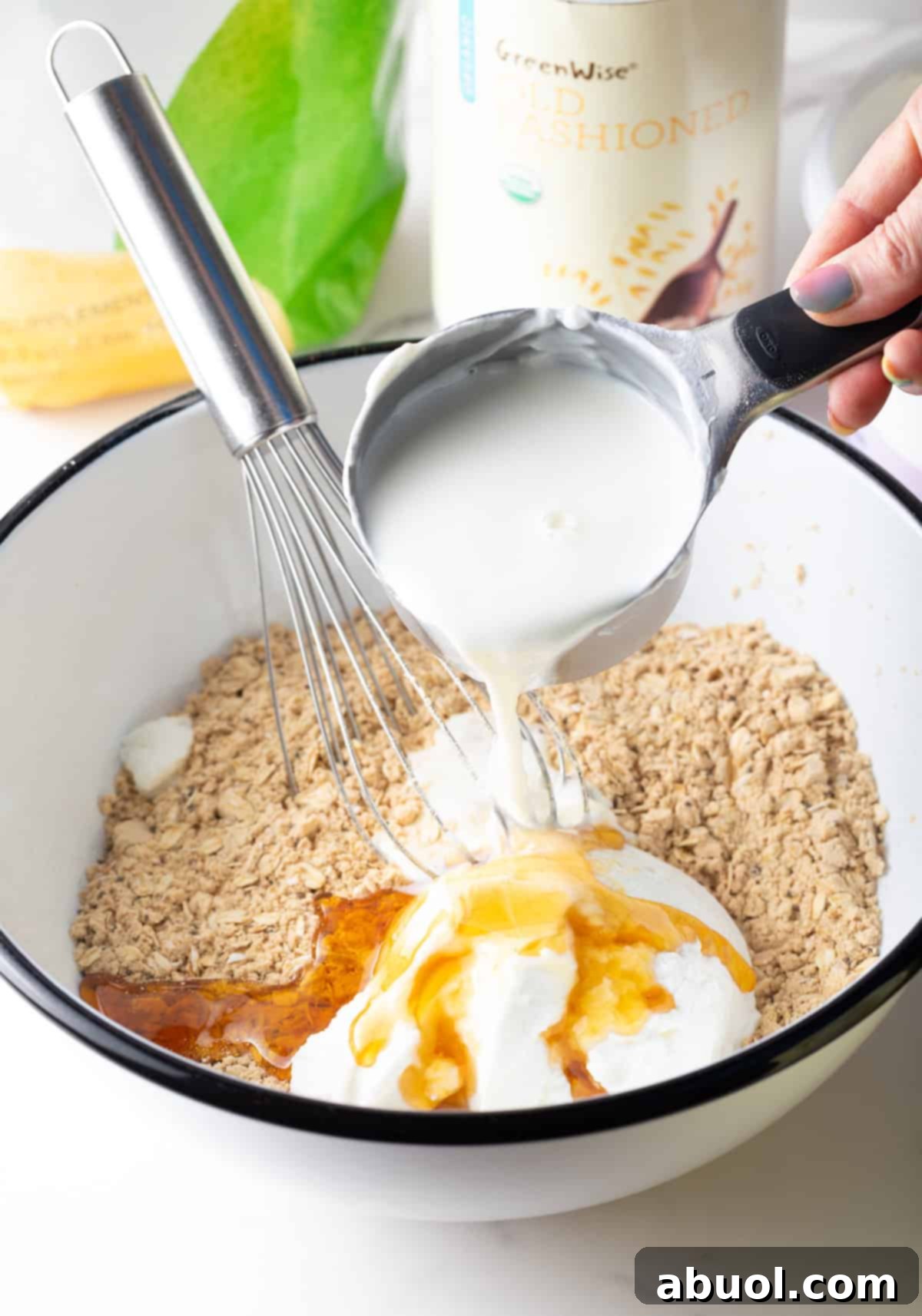 Pouring milk over ingredients for high-protein overnight oats