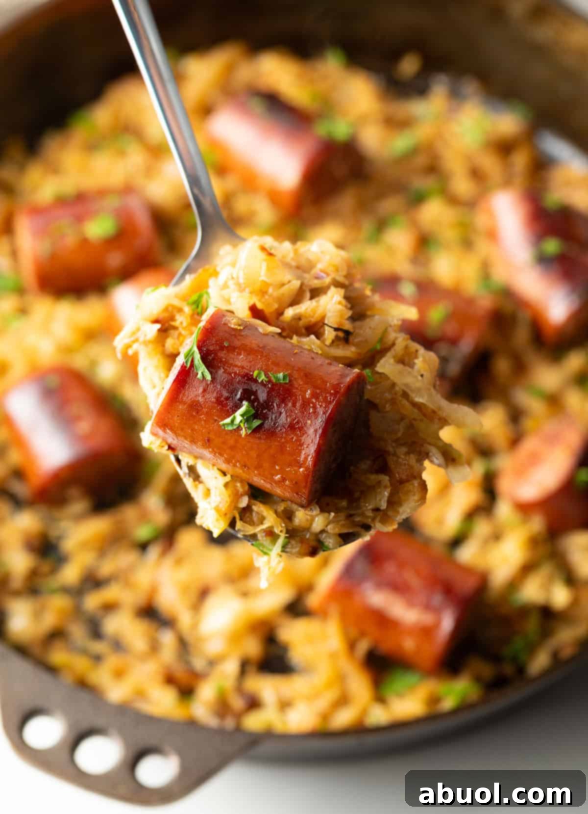Close-up of cooked sausage with sauerkraut on a spoon