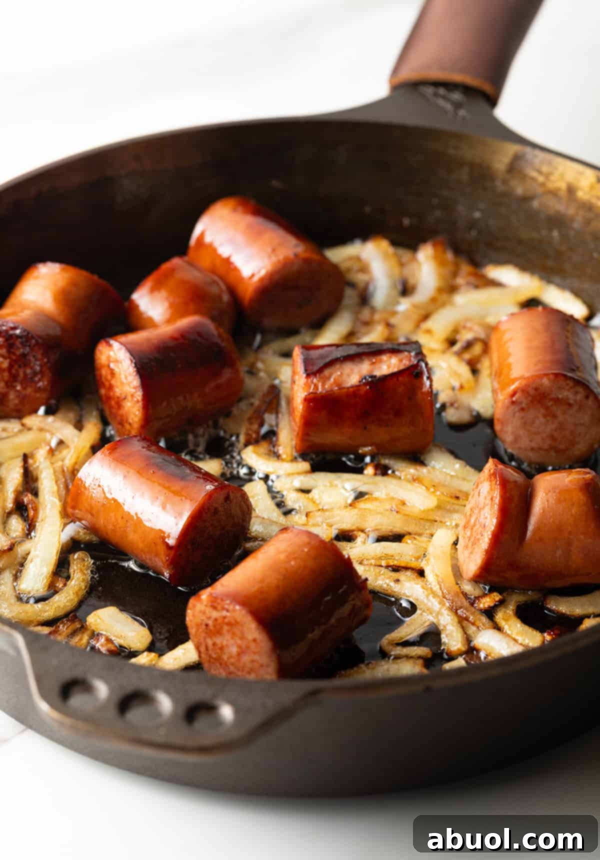 Seared kielbasa cooking in a skillet with onions