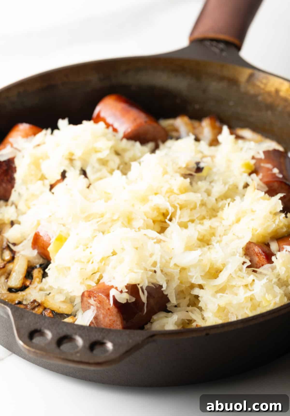 Skillet with kielbasa on top of sauerkraut