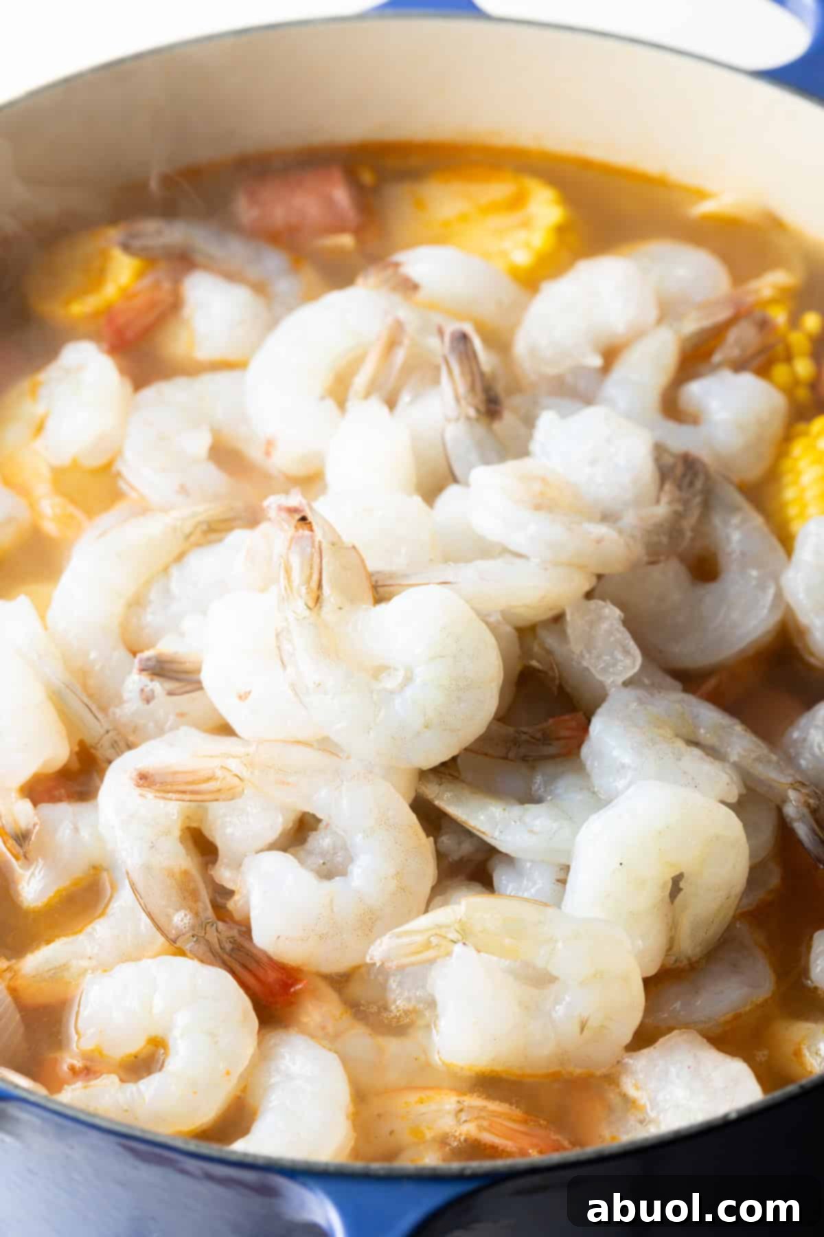 Raw shrimp is being added to the pot for low country shrimp and sausage boil recipe.