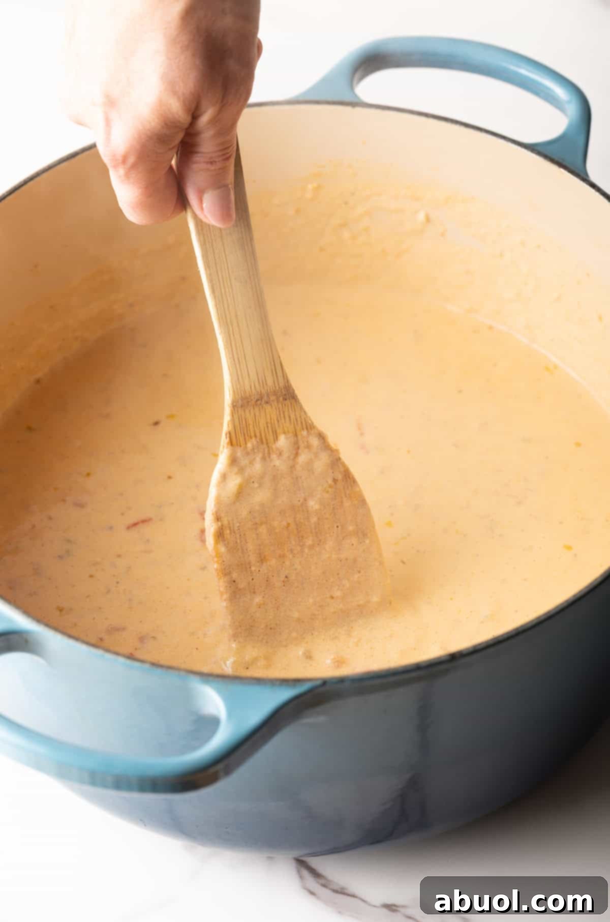 A wooden spoon stirring the roux mixture