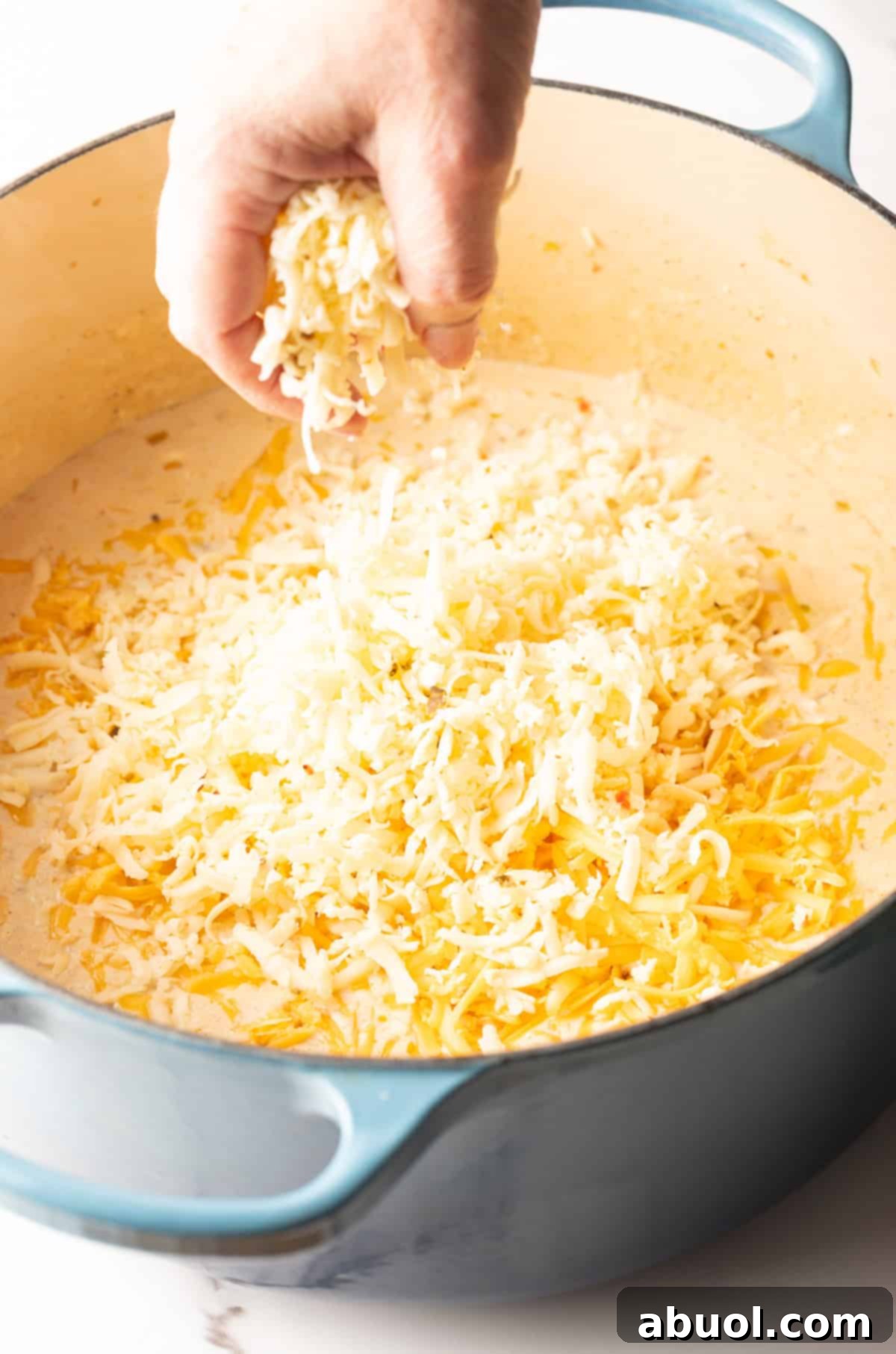 Grated cheese being added to the cream mixture