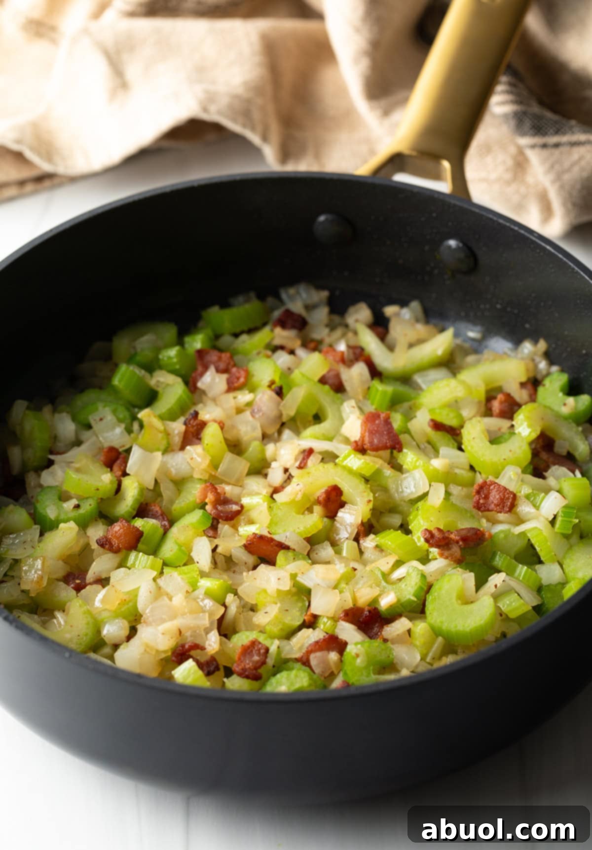Savory Slow Cooker Chicken Stew 6 Diced bacon, celery, and onions sautéing in a large black pan.