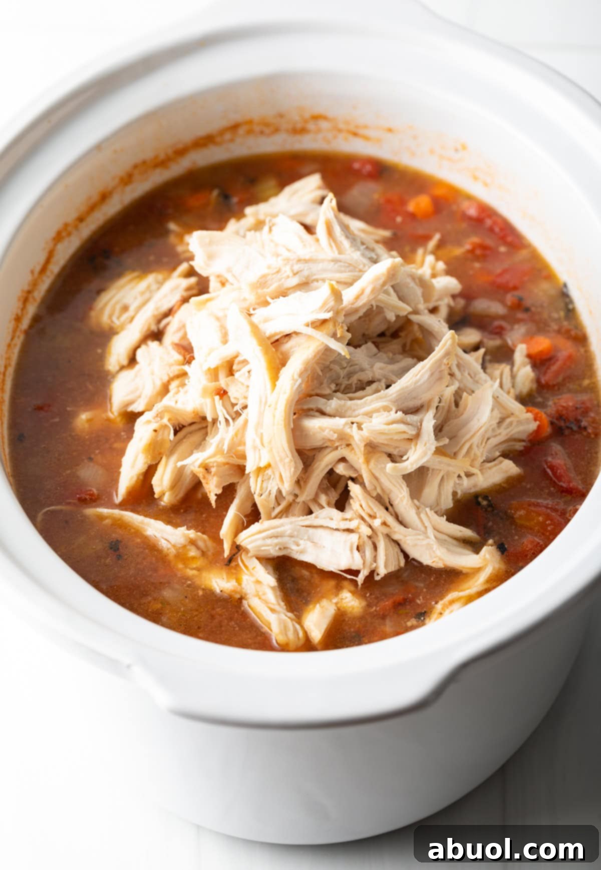 Savory Slow Cooker Chicken Stew 9 Shredded chicken over a tomato soup base in a slow cooker.