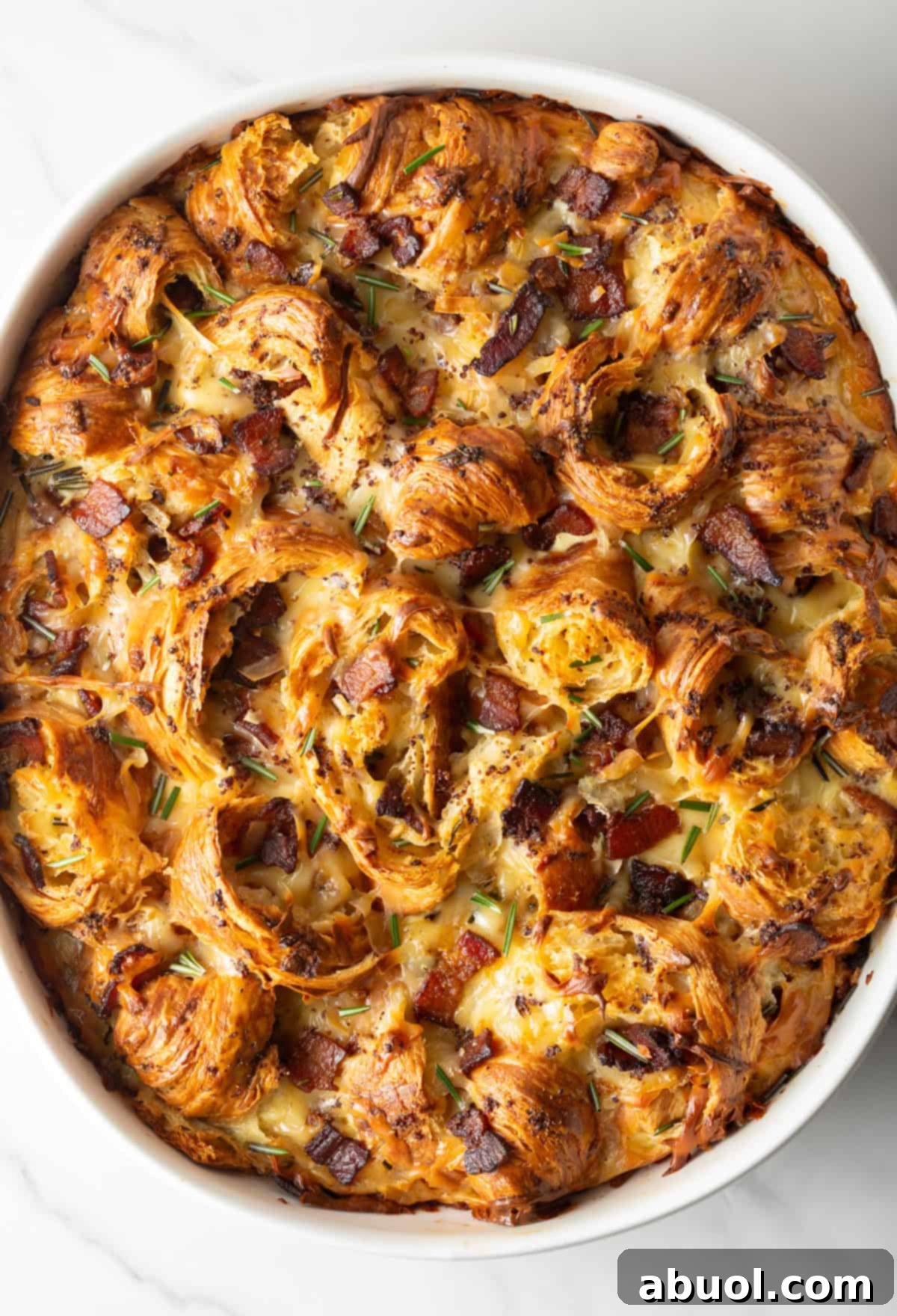 Overhead shot of croissant breakfast casserole recipe in a white baking dish, fresh from the oven.