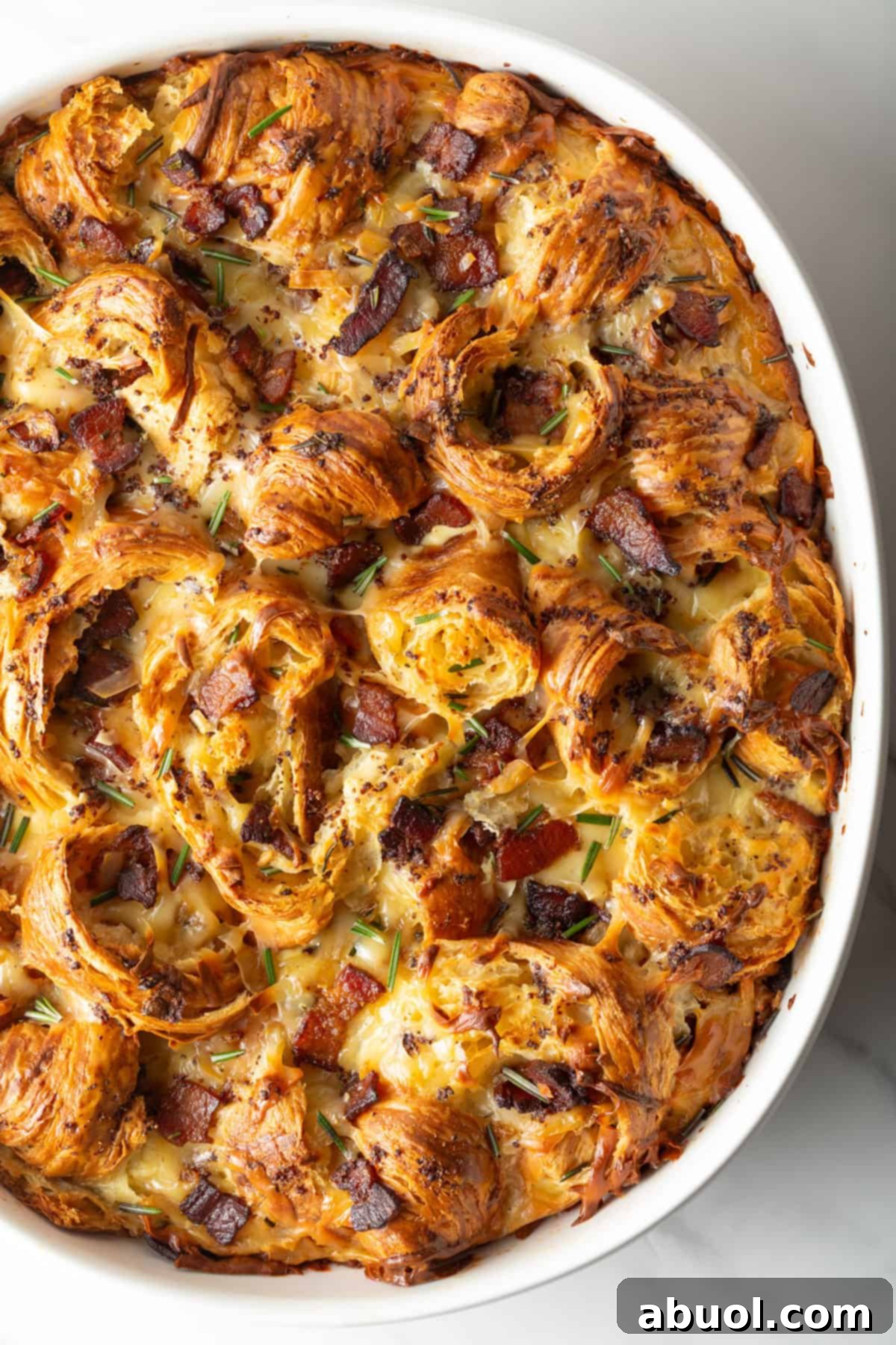 Overhead shot of croissant breakfast casserole recipe in a white baking dish, fresh from the oven.