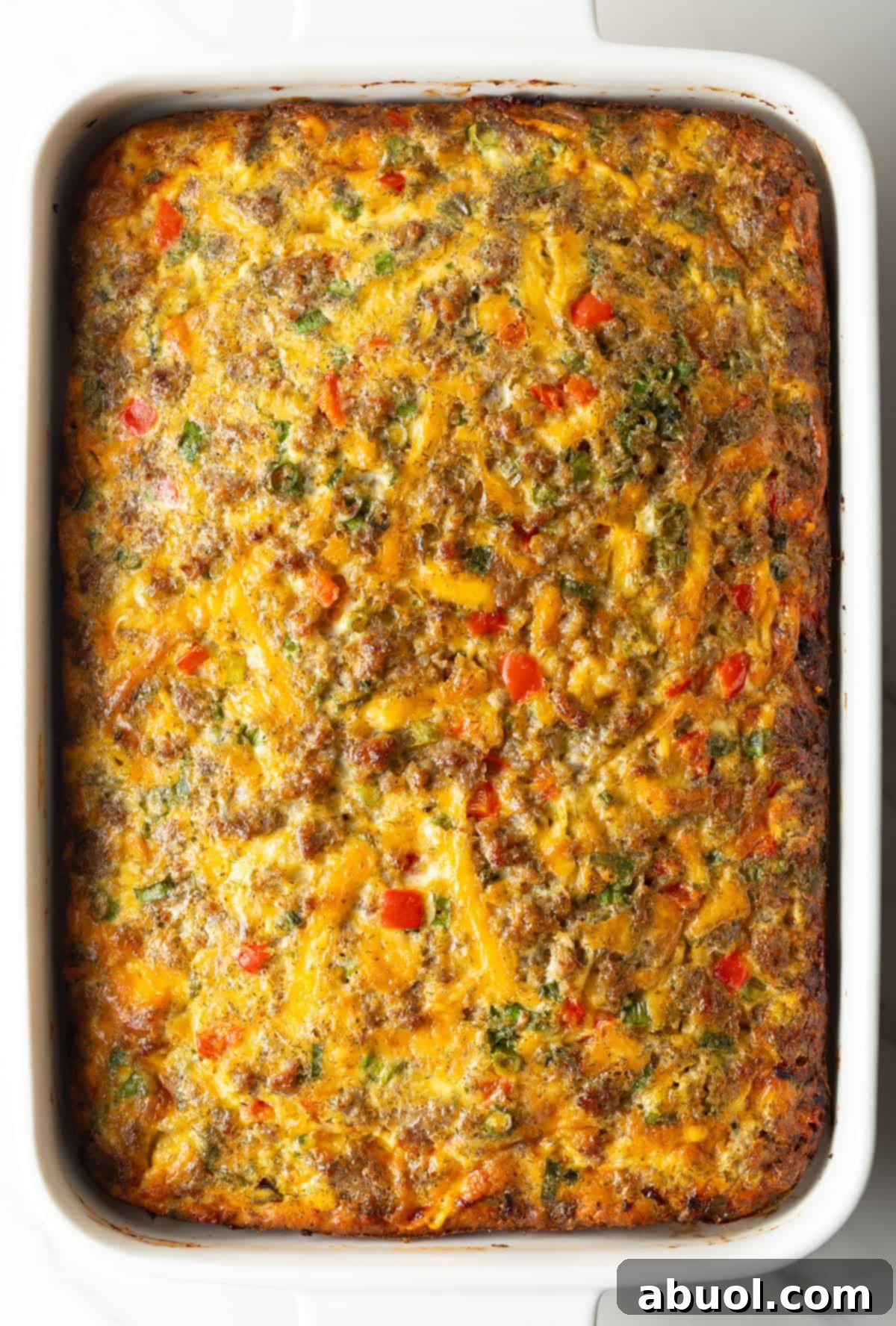 Top down view baked egg sausage and cheese casserole in a white rectangle dish