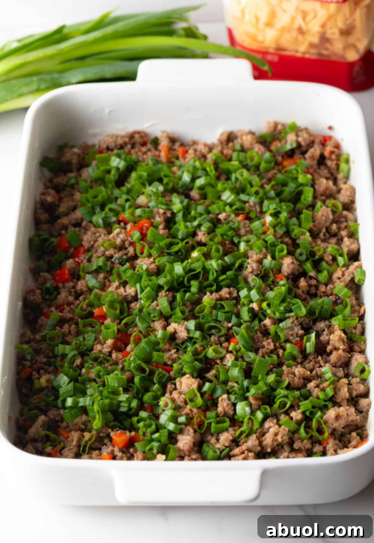 Cooked sausage and pepper mixture evenly spread in a baking dish