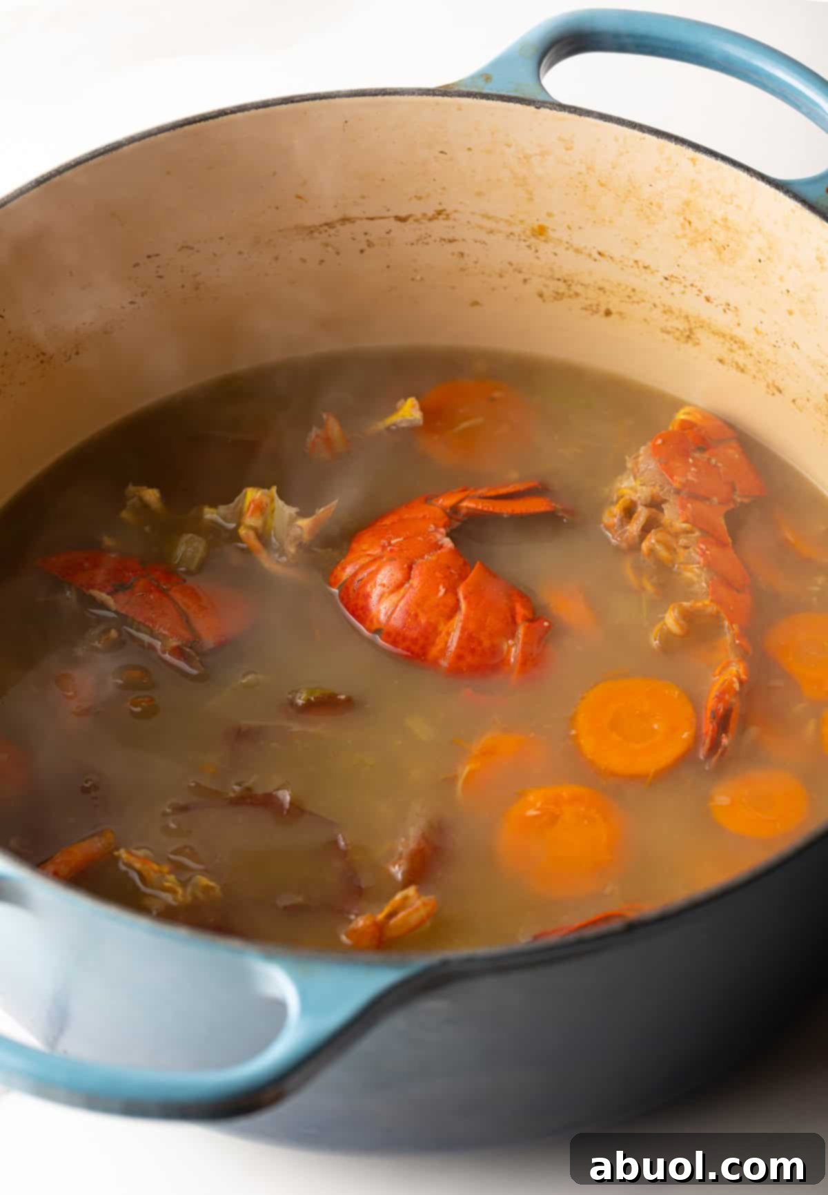 A pot simmering with seafood stock, lobster shells, and veggies.