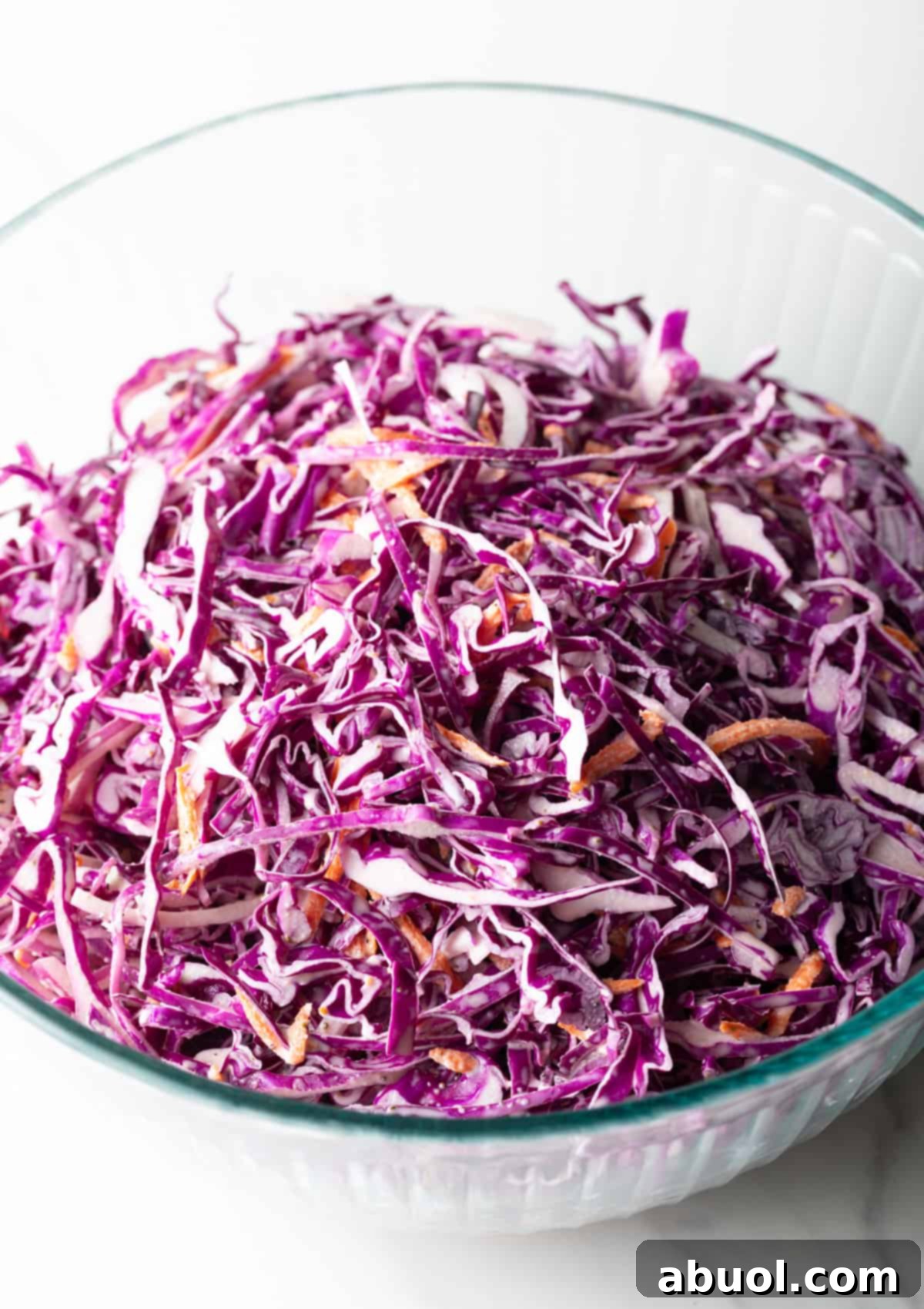 Overhead view of the vibrant red cabbage slaw in a glass bowl, highlighting the colorful ingredients.