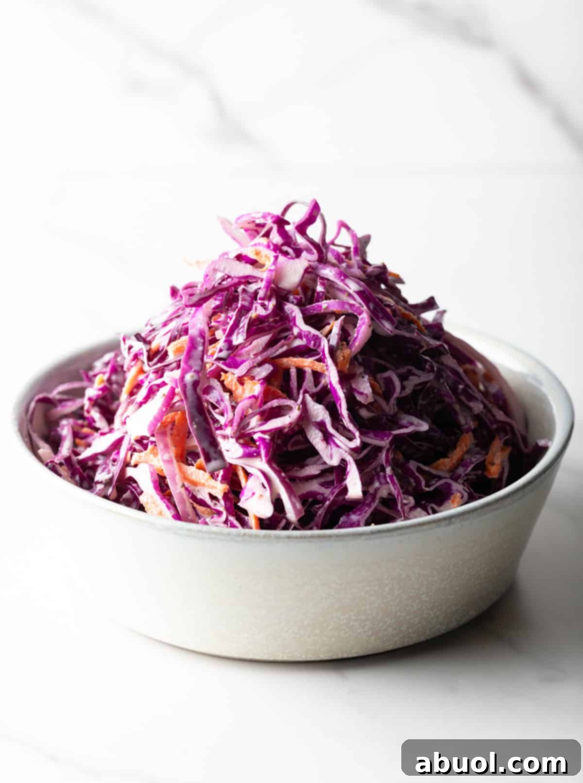 A white bowl overflowing with the creamy red cabbage slaw, ready to be served.