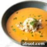 A black bowl filled with creamy crab bisque soup with crab meat and parsley on top.