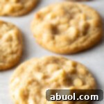 Close up view of three white chocolate macadamia nut cookies on parchment.