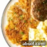 Crispy homemade hash browns, breakfast sausage, and scrambled eggs on a white plate.