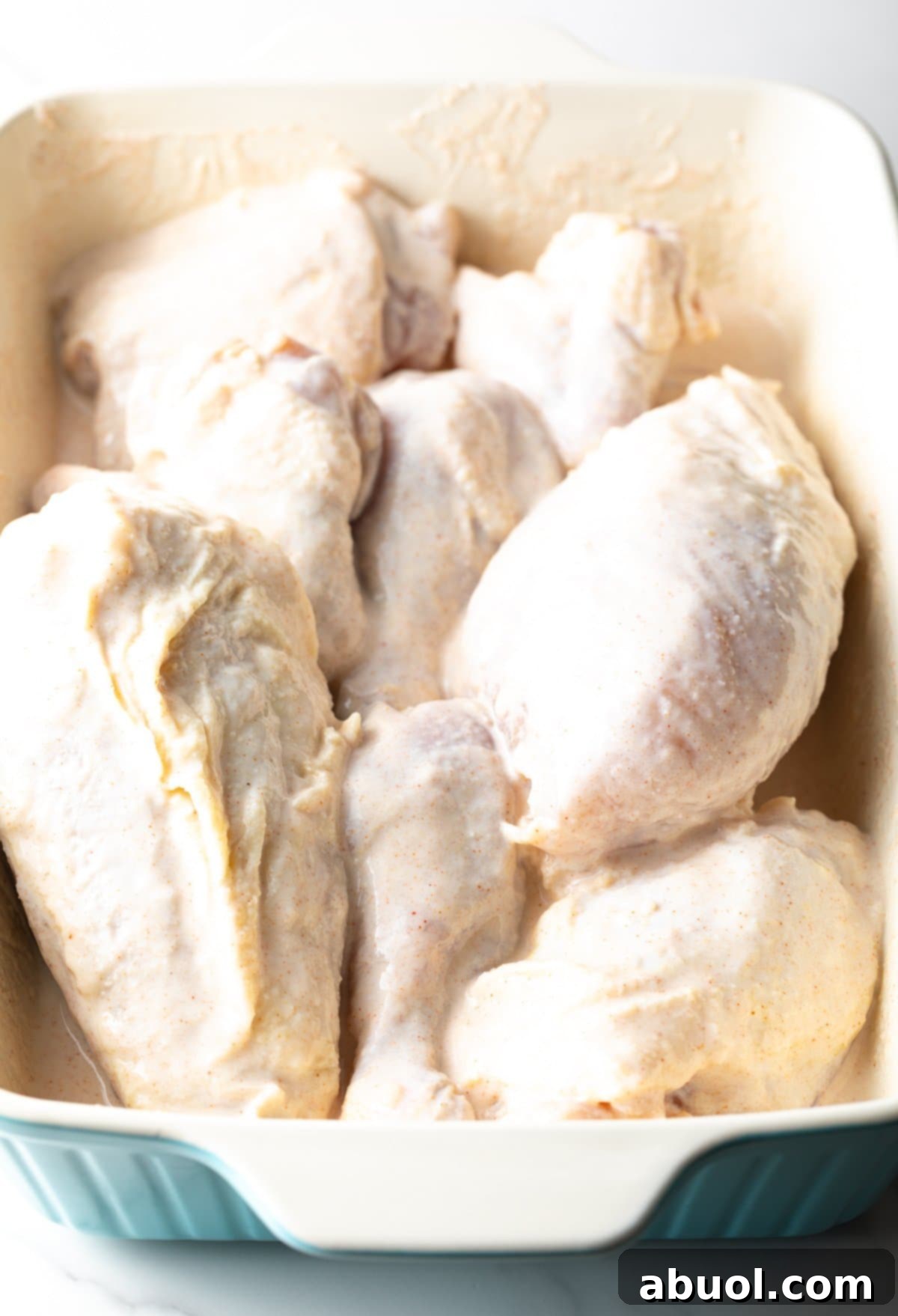 Southern Cast Iron Fried Chicken 6 Chicken pieces marinating in a flavorful buttermilk mixture sitting in a white baking dish.