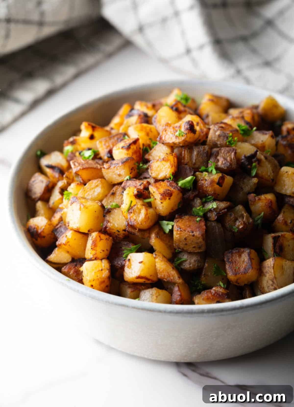 Golden Pan Fried Potatoes 4 A close-up shot of crispy home fries in a white bowl, showing their golden texture.