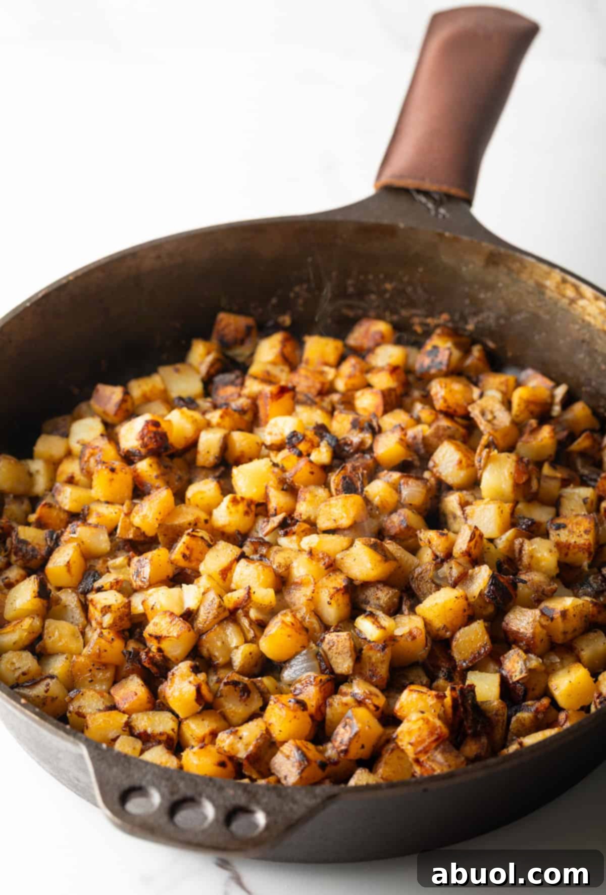 Golden Pan Fried Potatoes 7 Crispy, golden brown skillet fried potatoes cooking in a large cast-iron pan.