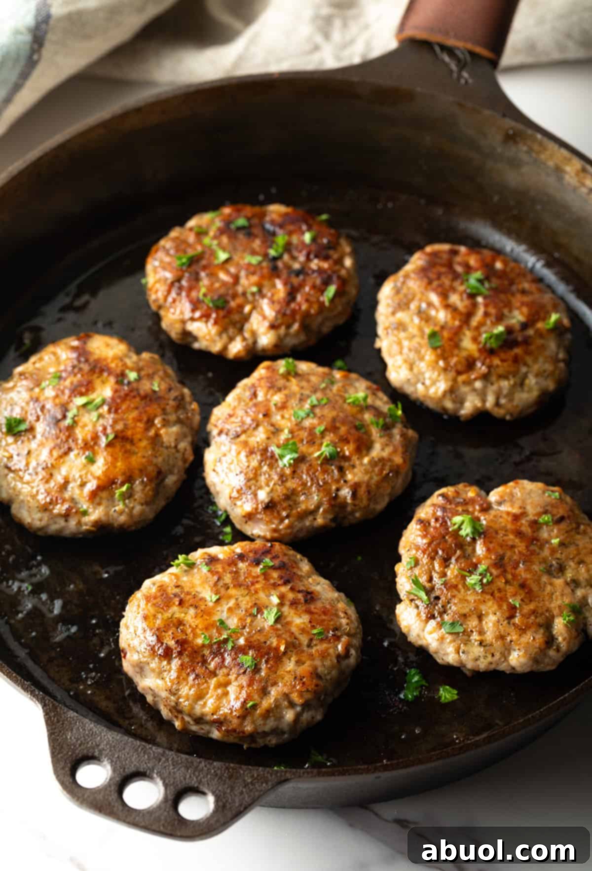 Homemade breakfast sausage patties browning beautifully in a cast-iron skillet.