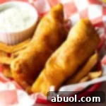 A basket of crispy beer-battered fried fish served over golden French fries.