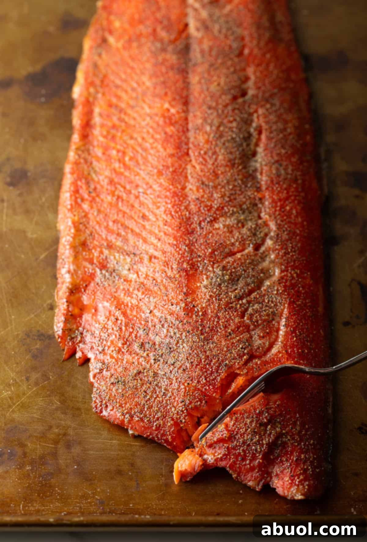 A perfectly cooked fillet of homemade smoked salmon being flaked with a fork.