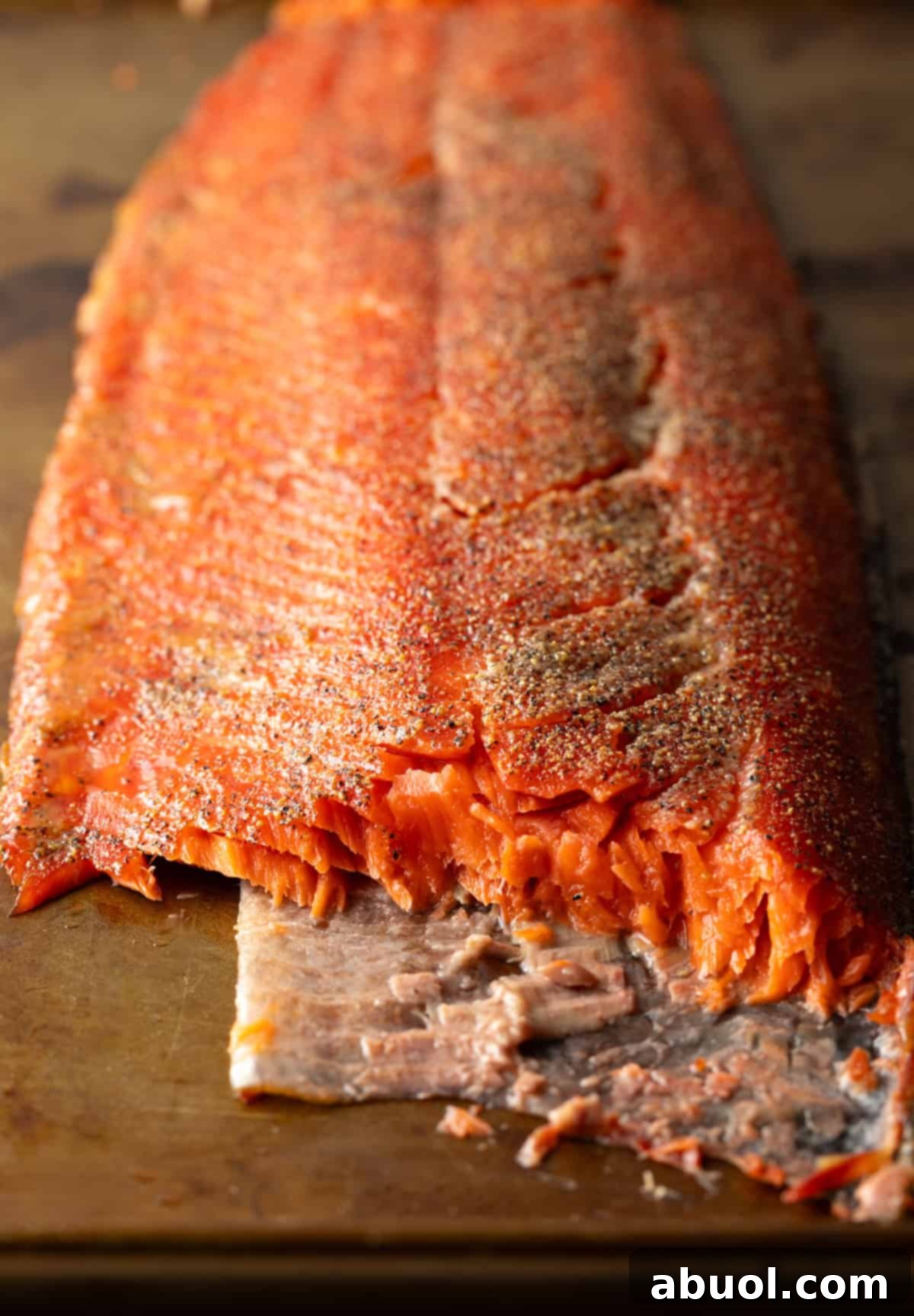 A full fillet of cold smoked salmon, sliced to reveal its moist, pink interior.