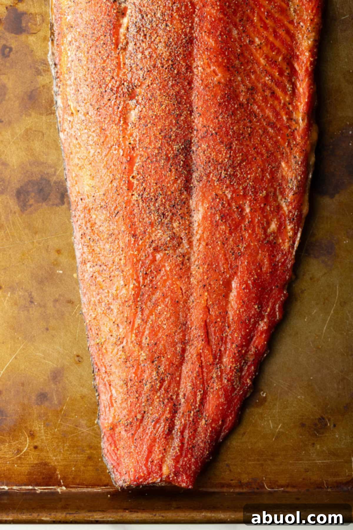 A whole fillet of freshly smoked salmon resting on a wooden board.