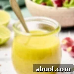 A honey lime dressing recipe in a glass jar with a spoon in it, ready for serving.