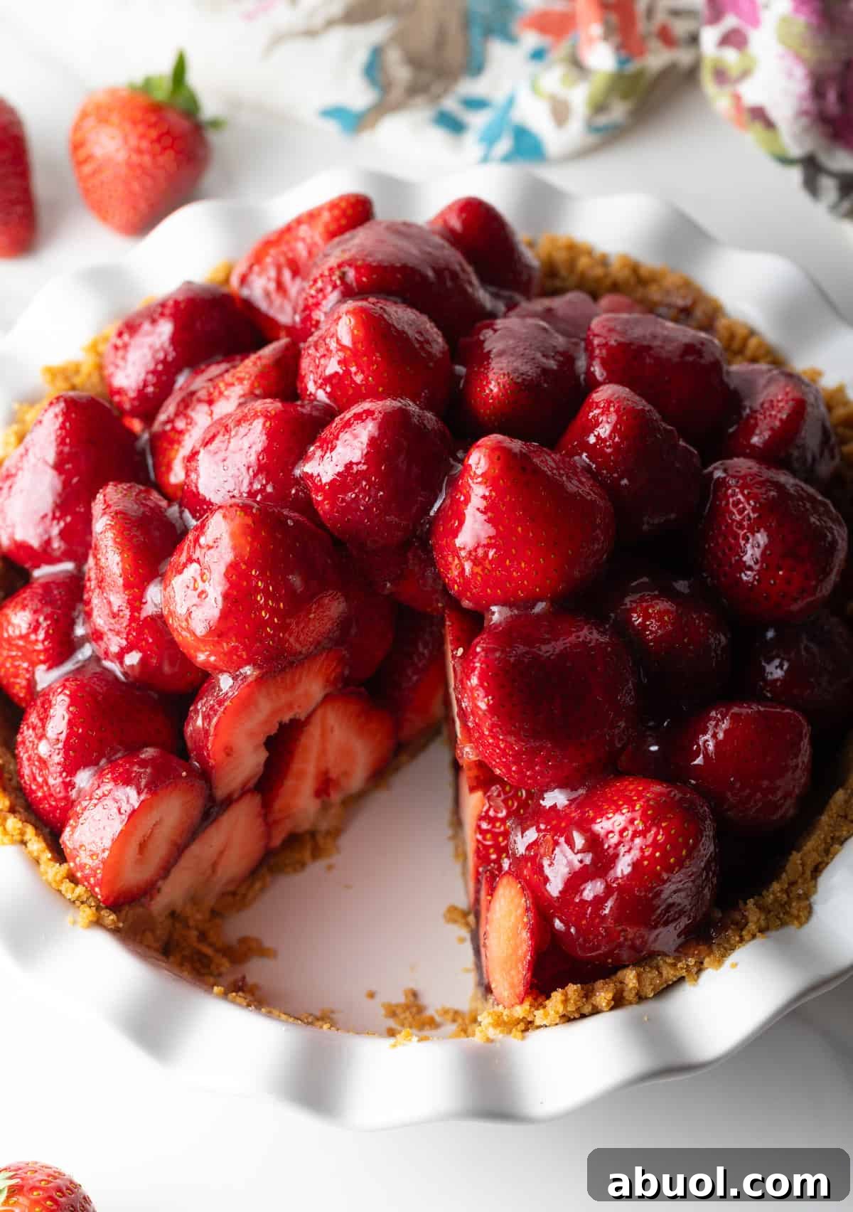 A no bake fresh strawberry pie in a pie pan with a slice taken out.