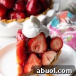 A slice of easy no-bake strawberry pie topped with whipped cream, sitting on a white plate.