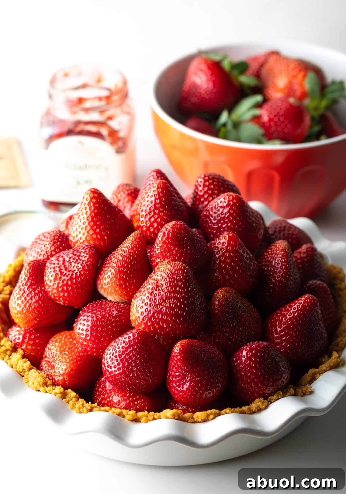 Fresh strawberries are stacked on a no bake strawberry pie crust.