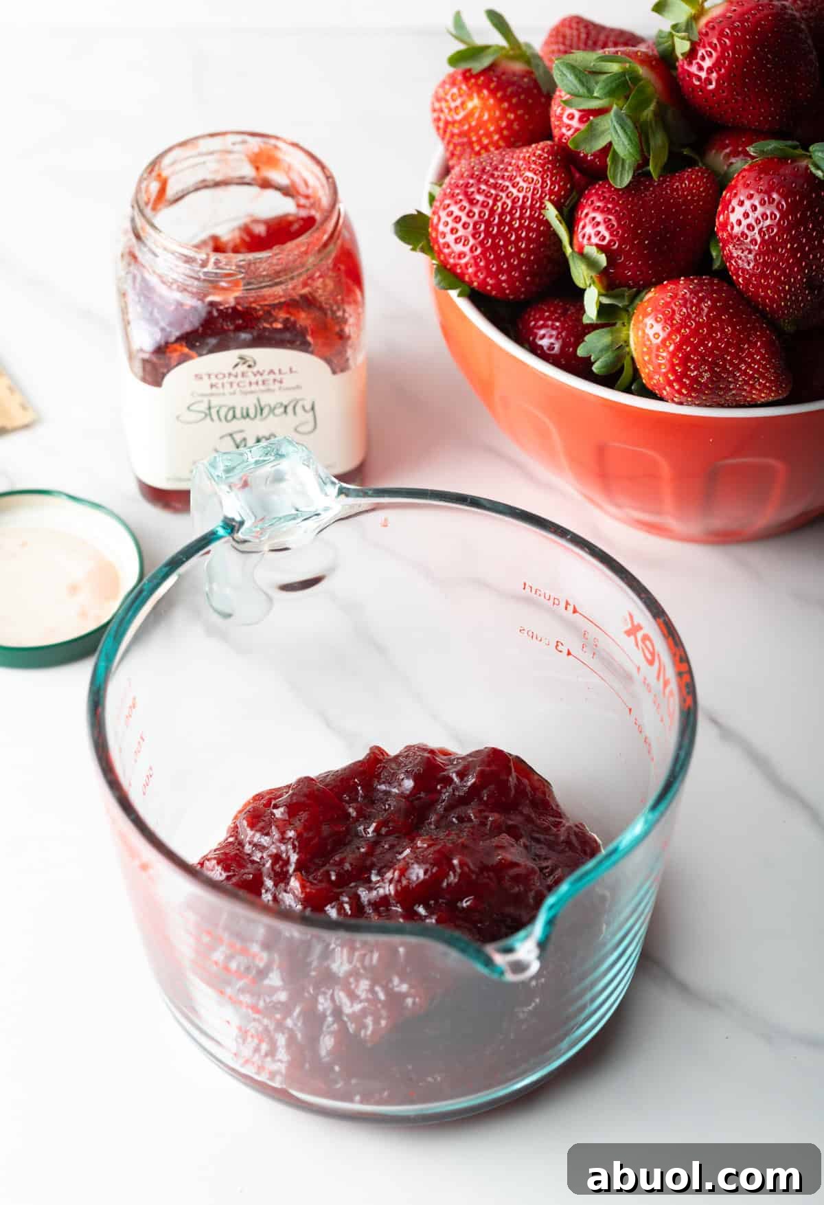A strawberry jam and gelatin mixture in a glass measuring bowl.
