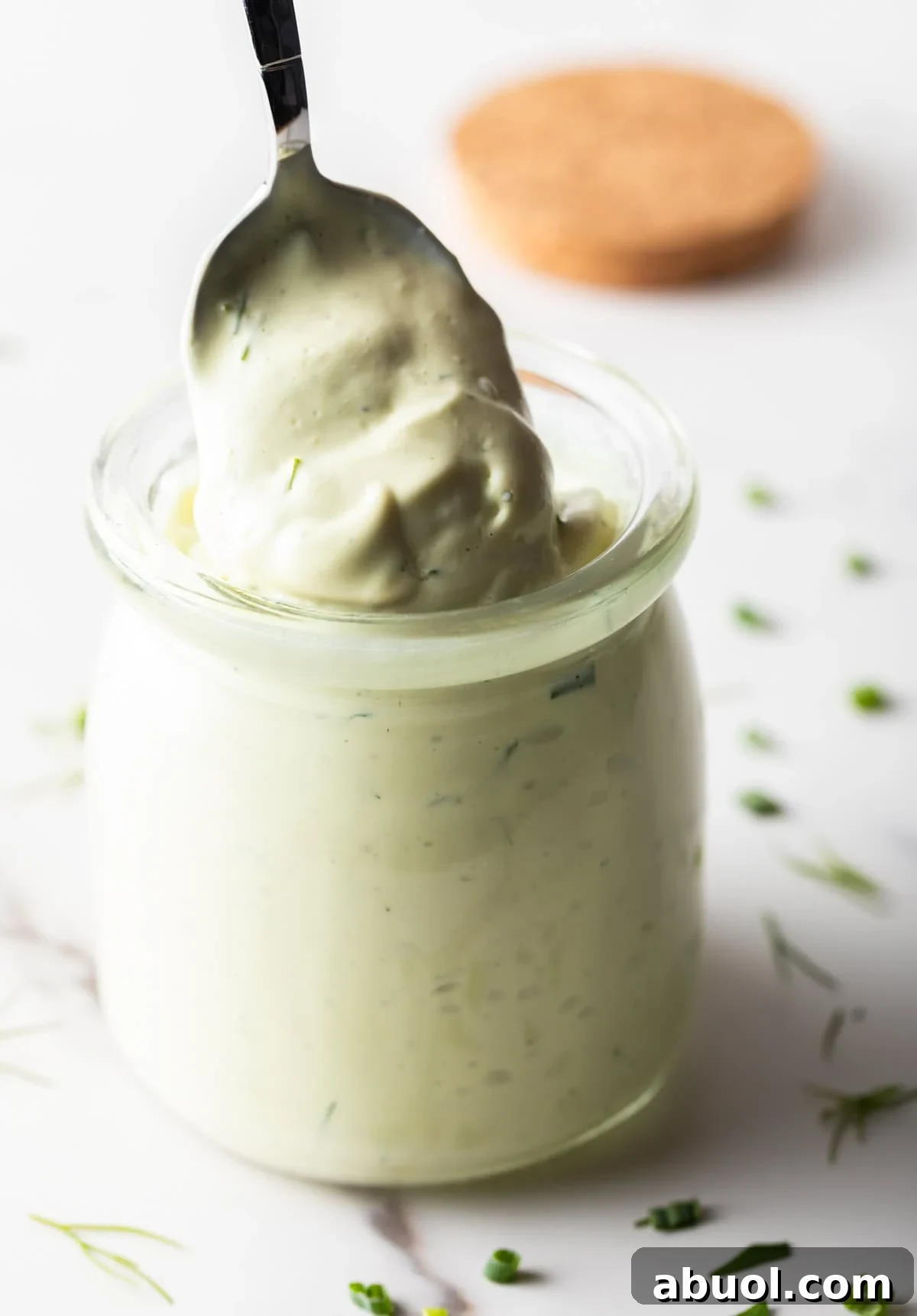 Creamy Avocado Lime Ranch Dressing Recipe 5 A spoon is scooping a serving of avocado ranch dressing from a glass jar.