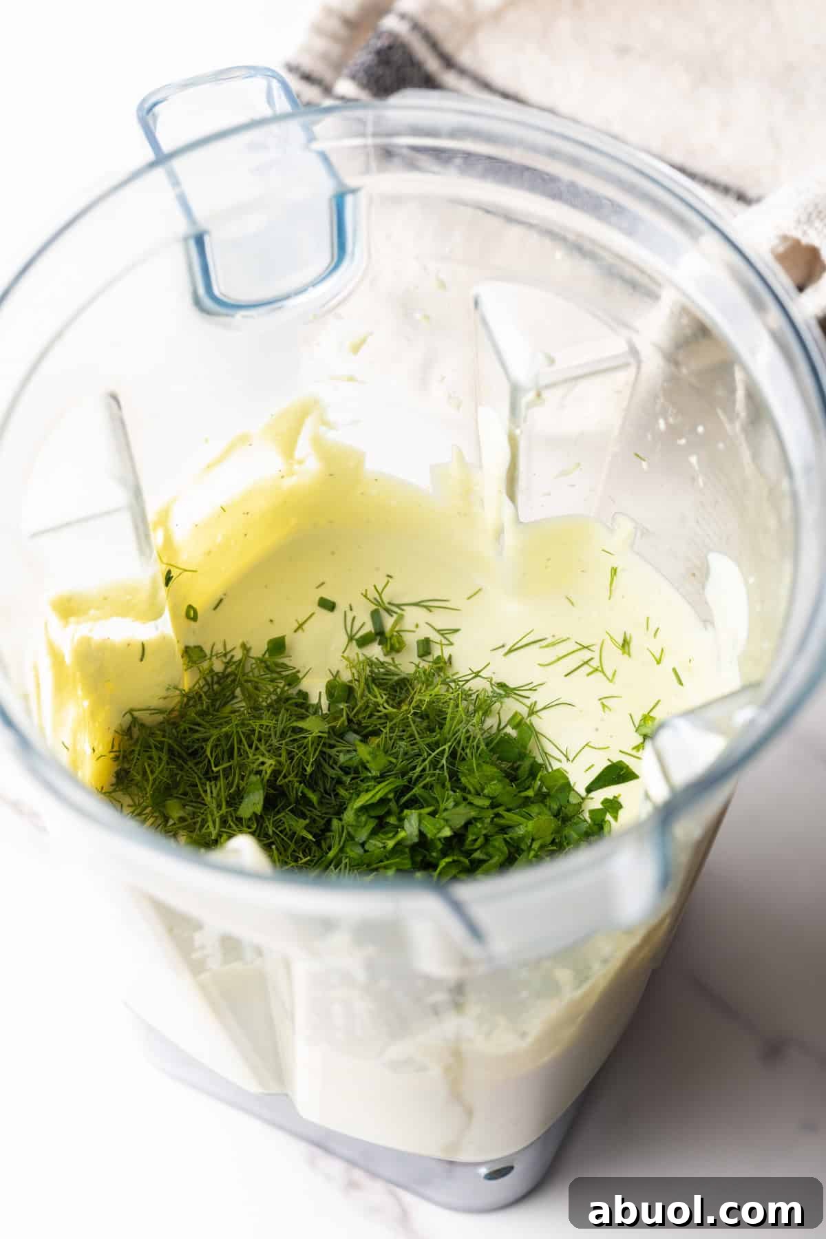 Creamy Avocado Lime Ranch Dressing Recipe 8 Fresh herbs are being incorporated into an avocado ranch dressing recipe with a blender.