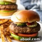 A thick and juicy ground turkey burger sitting on a white plate next to French fries.