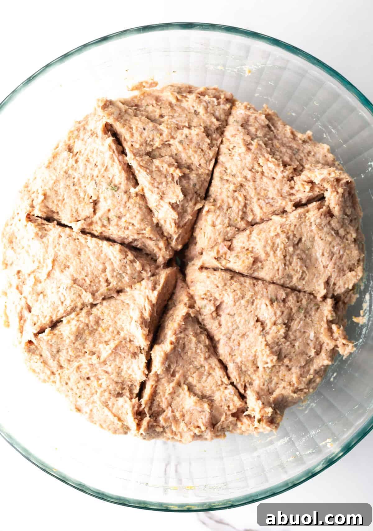A turkey burger mix in a glass bowl, divided into eight sections.
