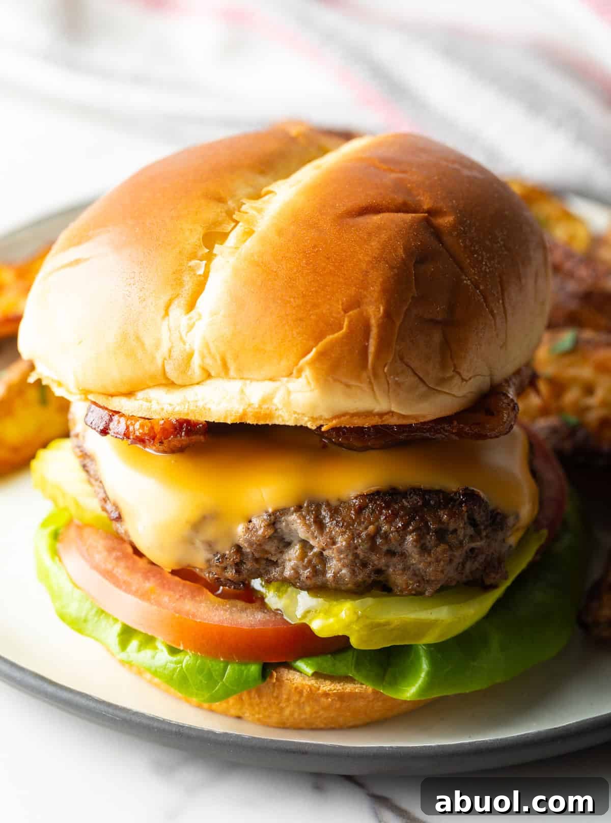 A juicy deer burger recipe featuring a deer burger patty between two buns and topped with cheese and condiments.