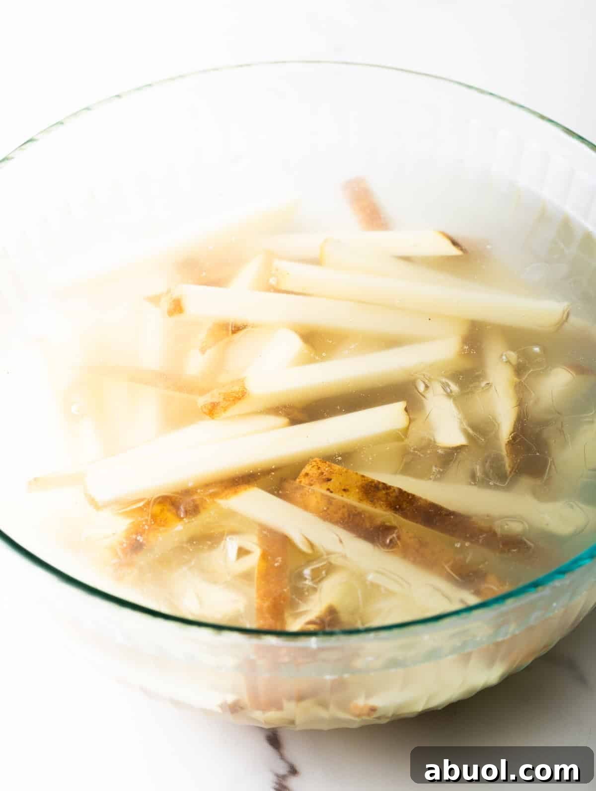 Raw potato slices sitting in an ice water bath.