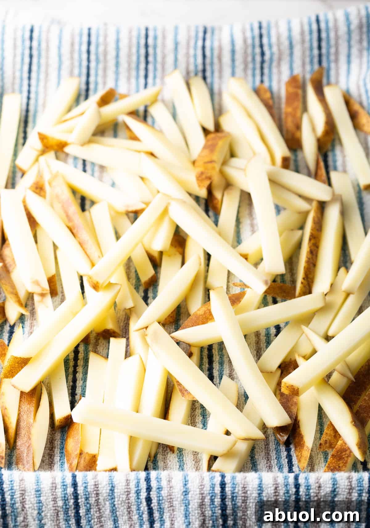 Raw French fries are being drained on a towel.