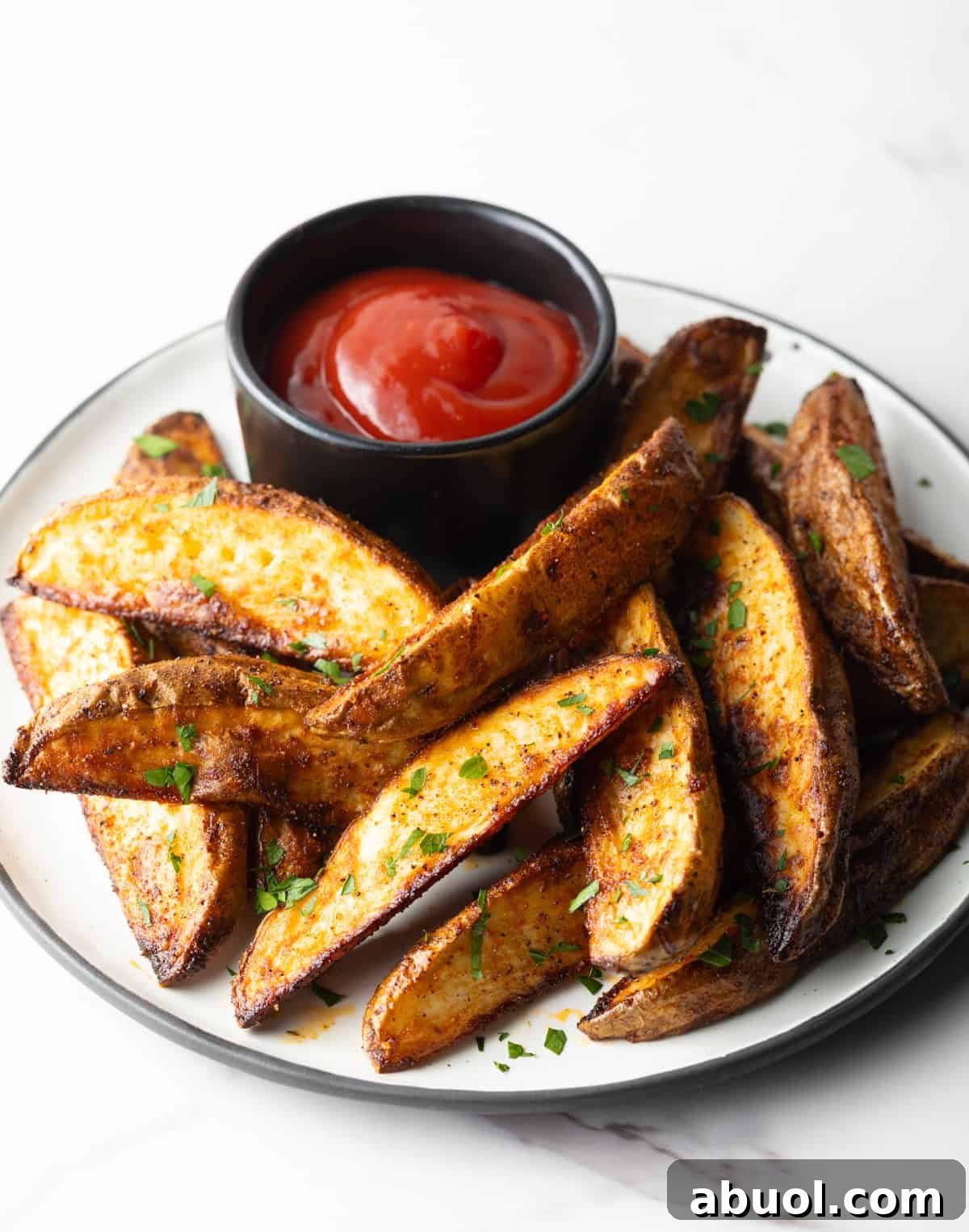 A plate of homemade baked potato wedges with a ramekin of ketchup.